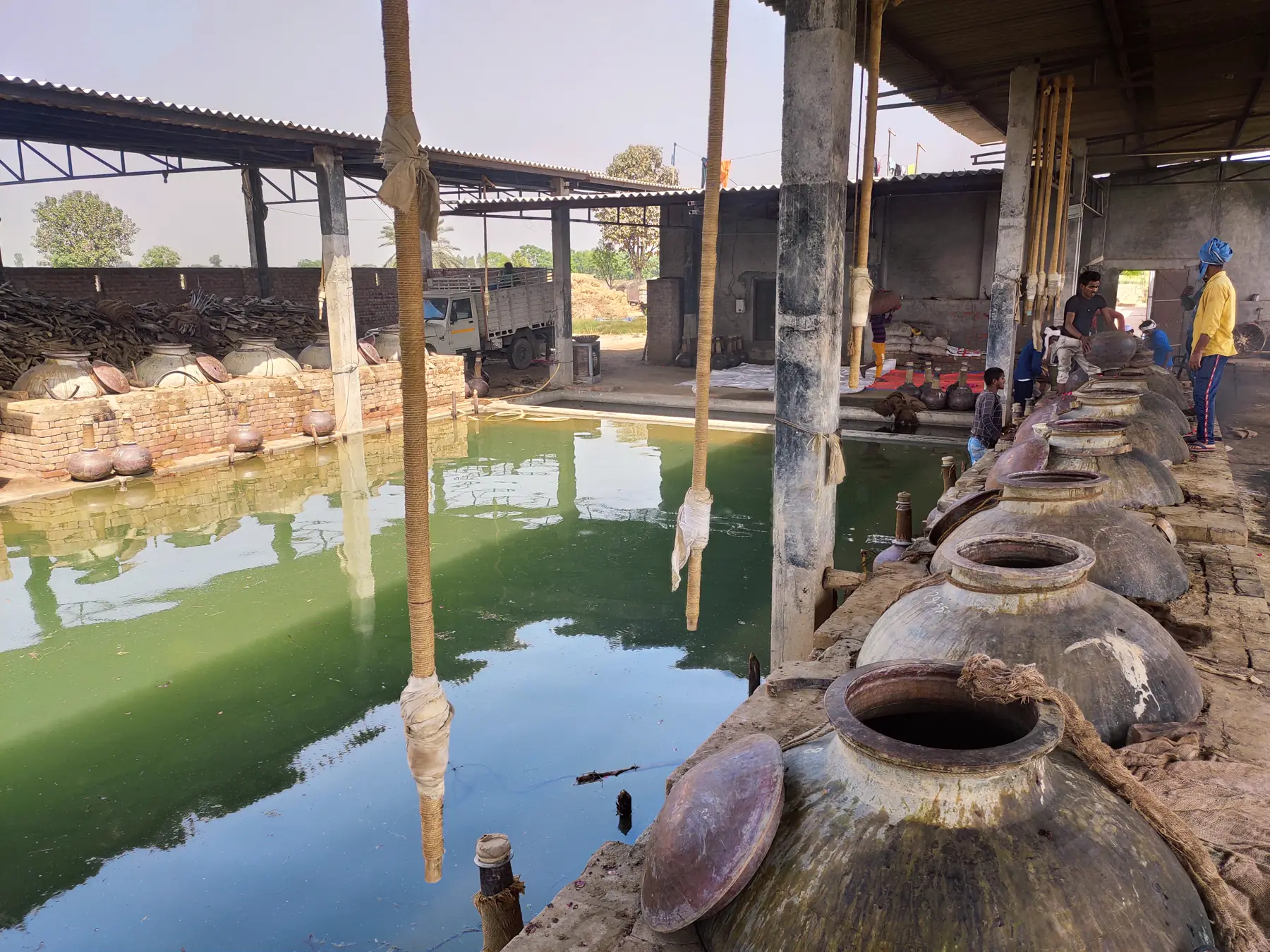 The Asam & Co. distillery yard in Kannauj — copper degs lined beside the cooling channel